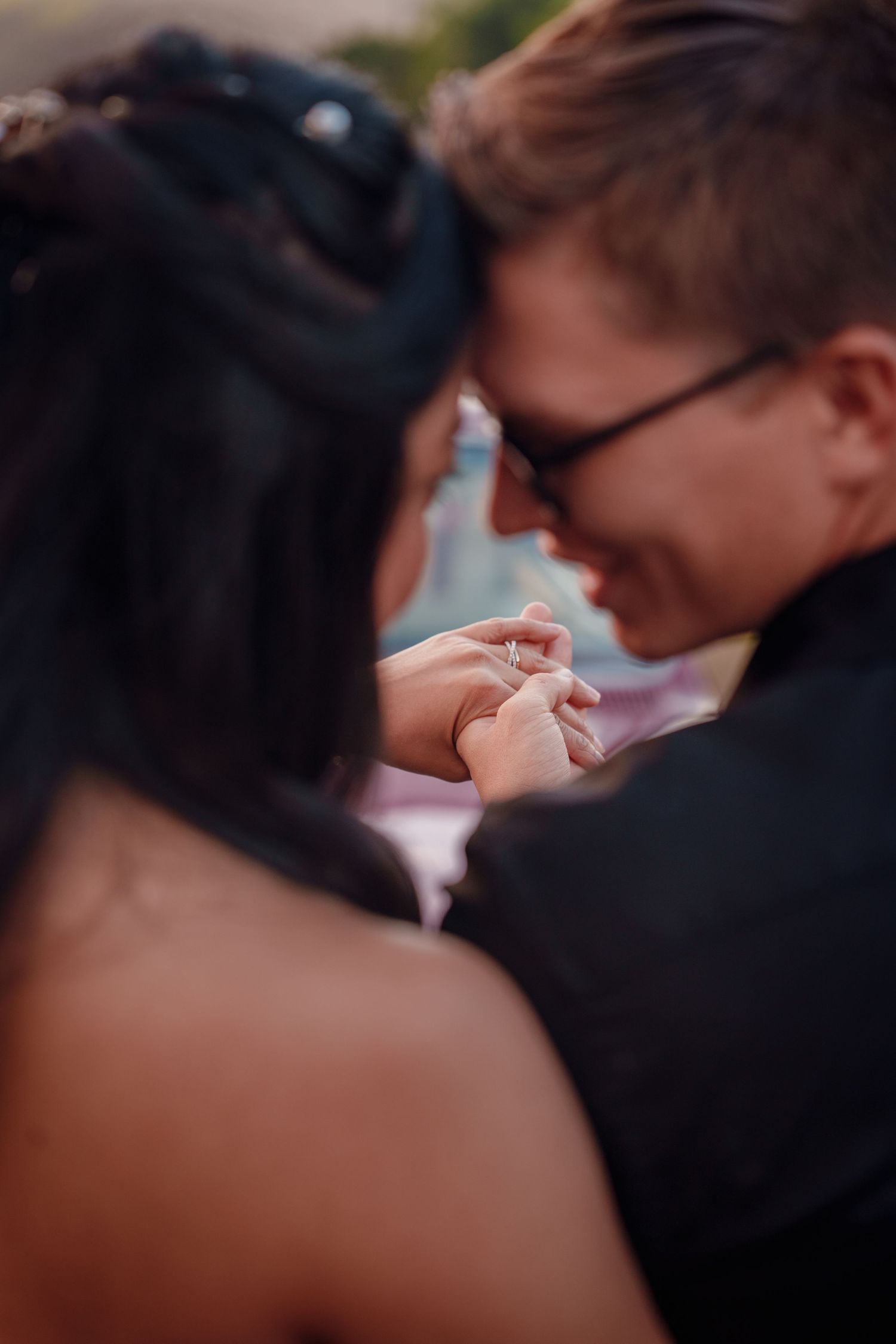 Romantic couple touching foreheads and holding hands tenderly during an intimate engagement moment.
