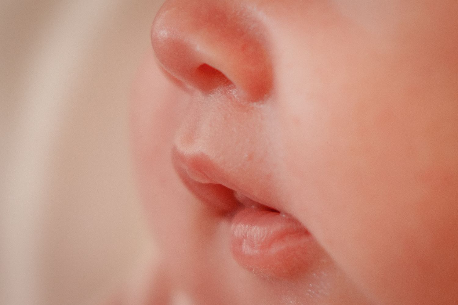 Close-up macro photo of a newborn baby's nose and lips showing soft, delicate skin texture.