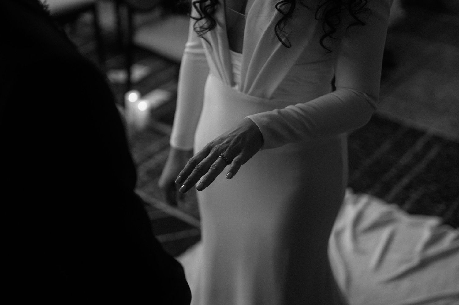 Close-up black and white photo of a bride in a white gown with delicate gloves at her wedding.