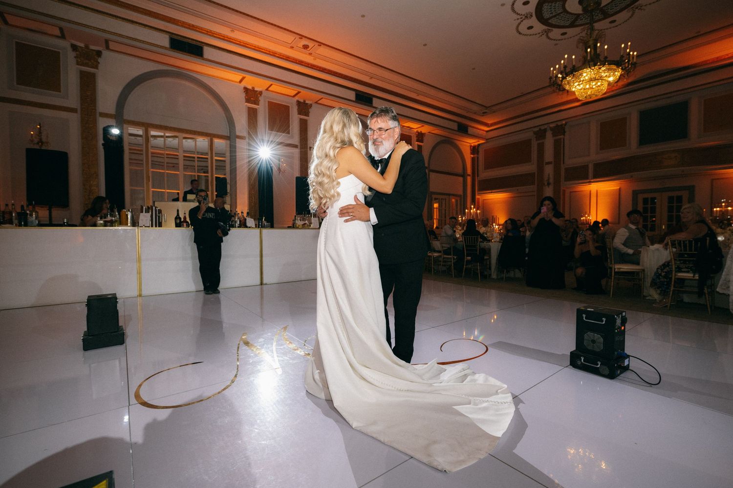 Bride and groom sharing their first dance on a white dance floor at wedding reception.