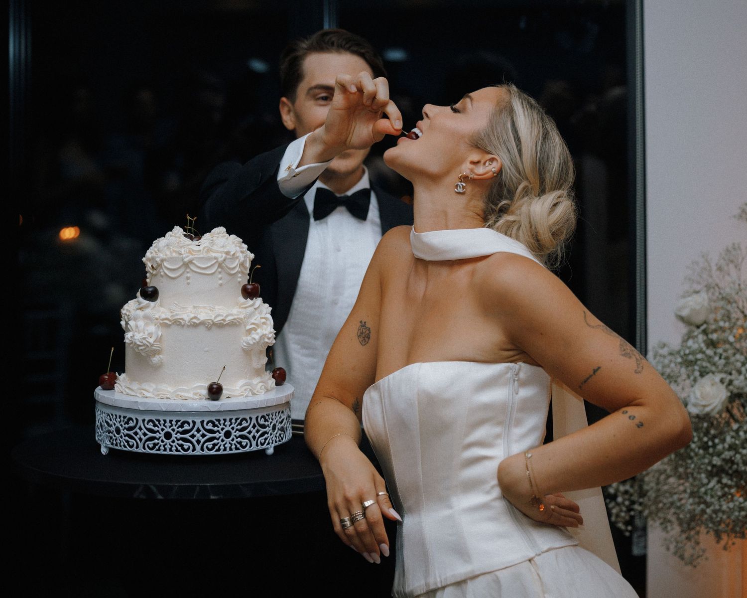 Groom feeding bride a piece of white wedding cake during fun reception cake cutting ceremony.