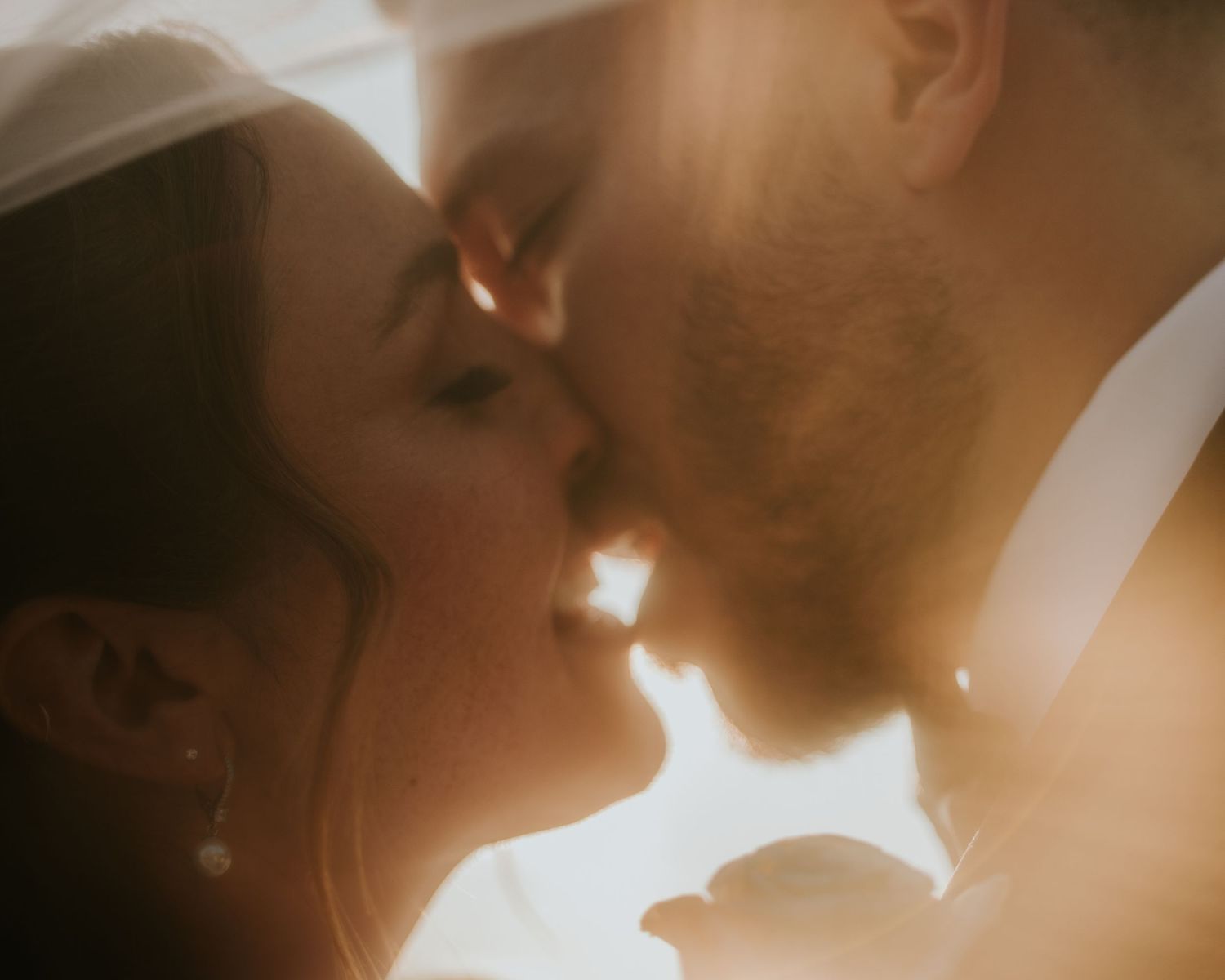 Bride and groom sharing romantic golden hour kiss on wedding day.