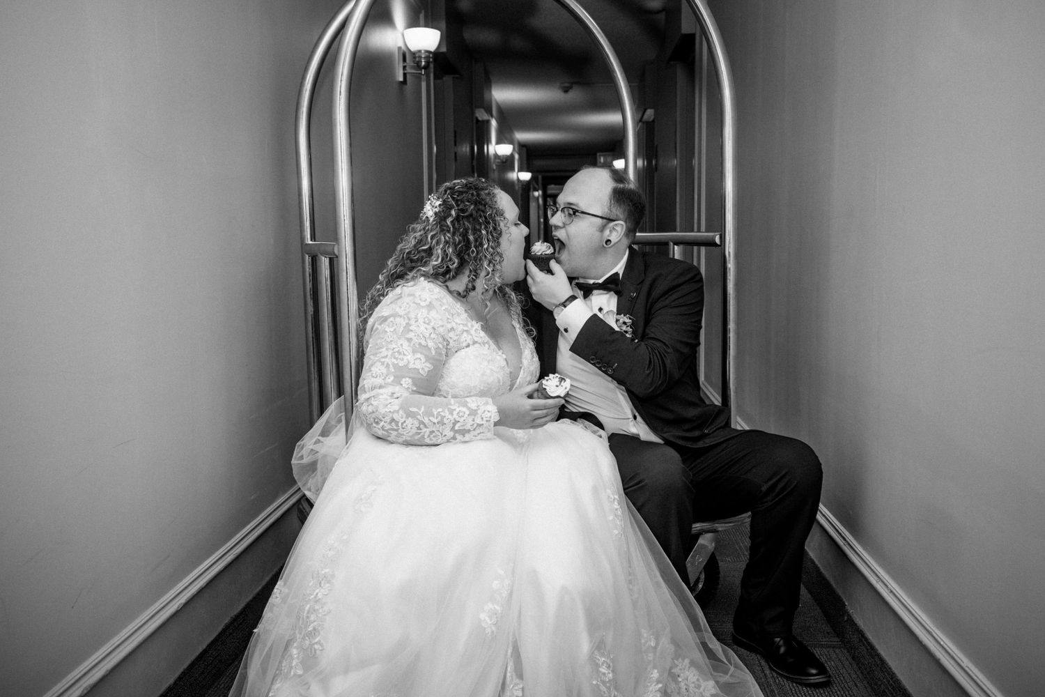 Black and white photo of a bride and groom sharing a romantic moment in a hallway.
