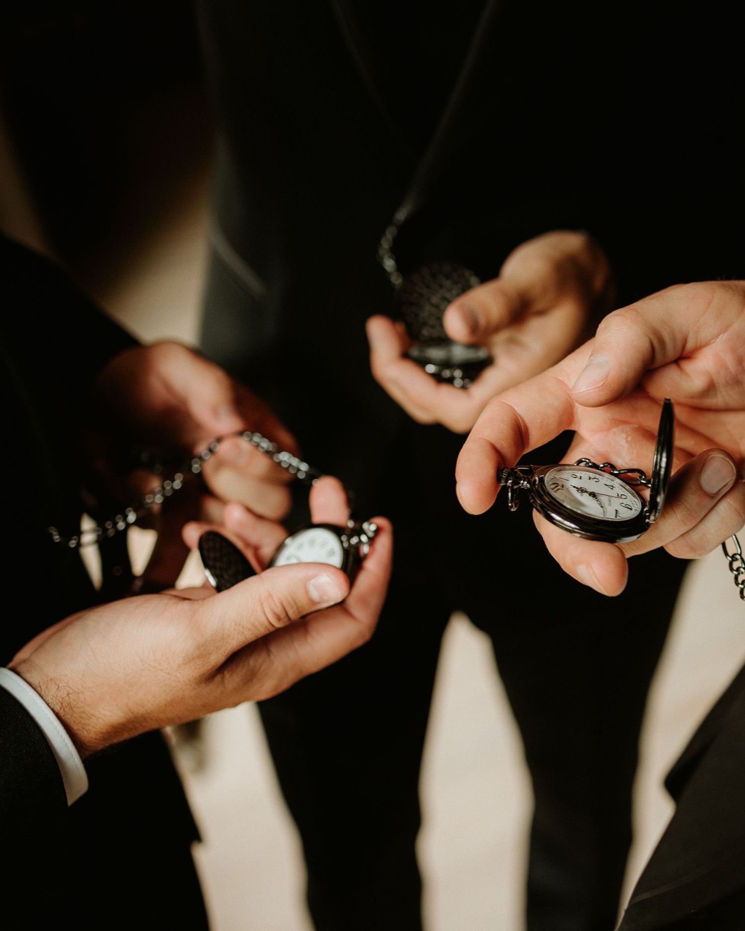 Groomsmen holding open pocket watches in their hands at a wedding ceremony.