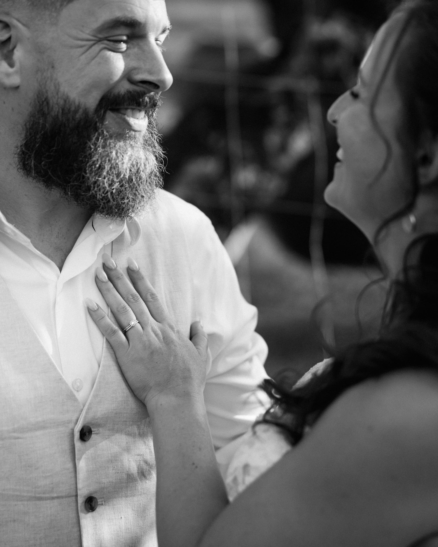 Bride placing hand on groom's chest, both smiling, black and white.