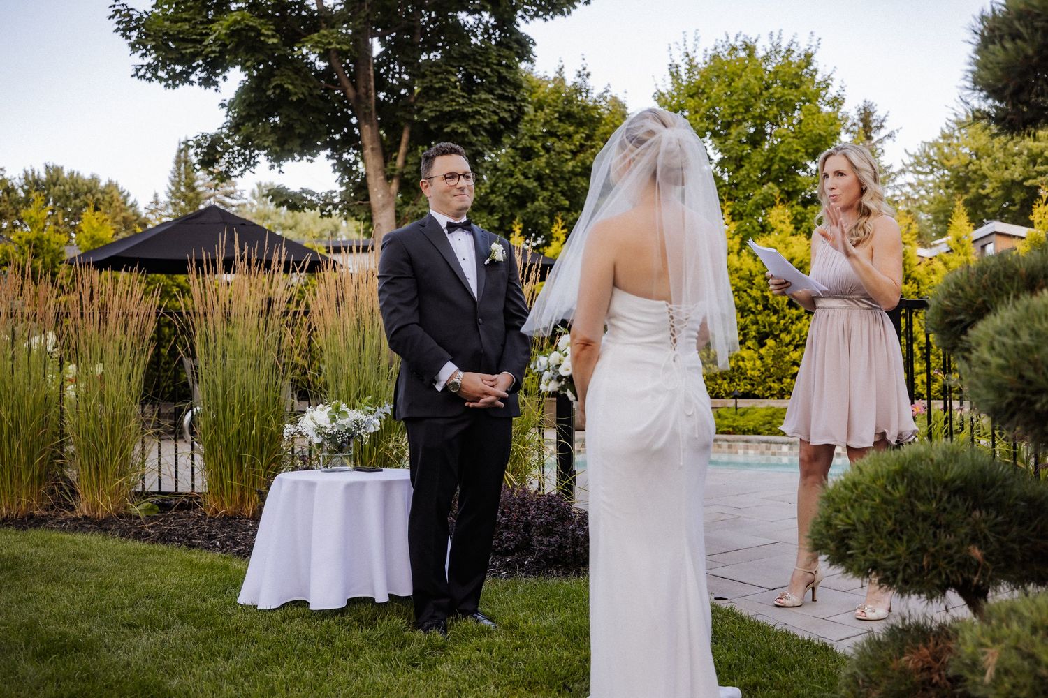 Outdoor wedding ceremony with bride and groom exchanging vows in garden setting.