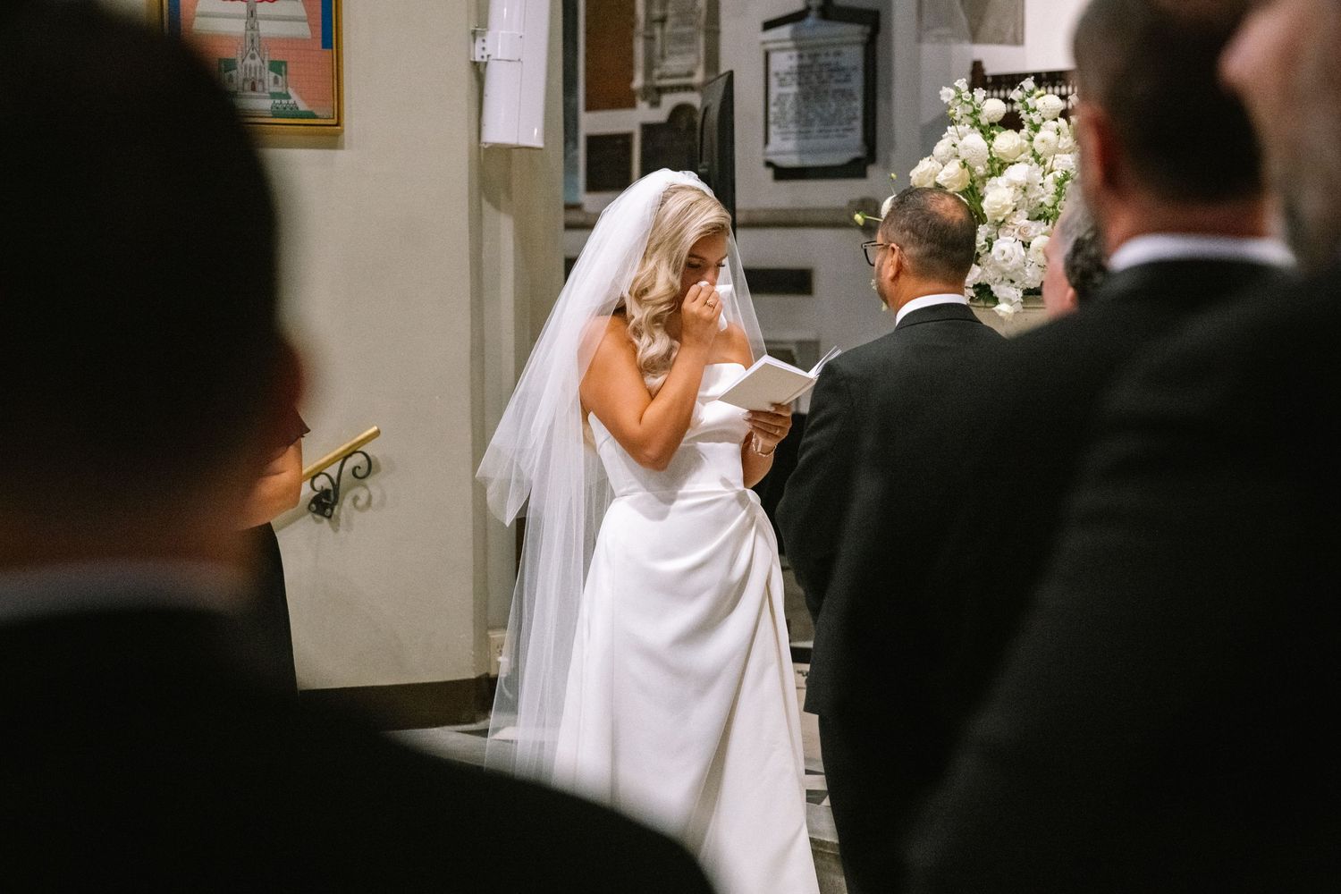 Emotional bride reading vows at the altar during a church wedding ceremony.