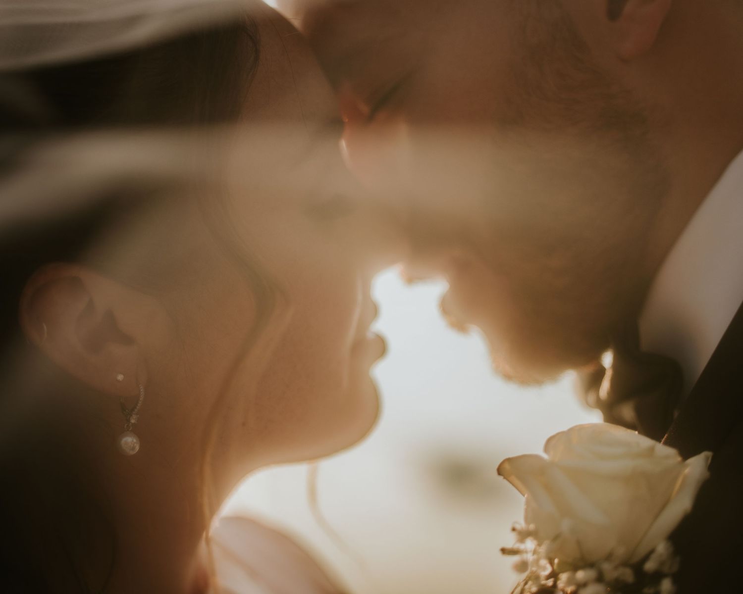 Romantic close-up of a bride and groom sharing an intimate moment, soft golden light illuminating their faces on their wedding day.