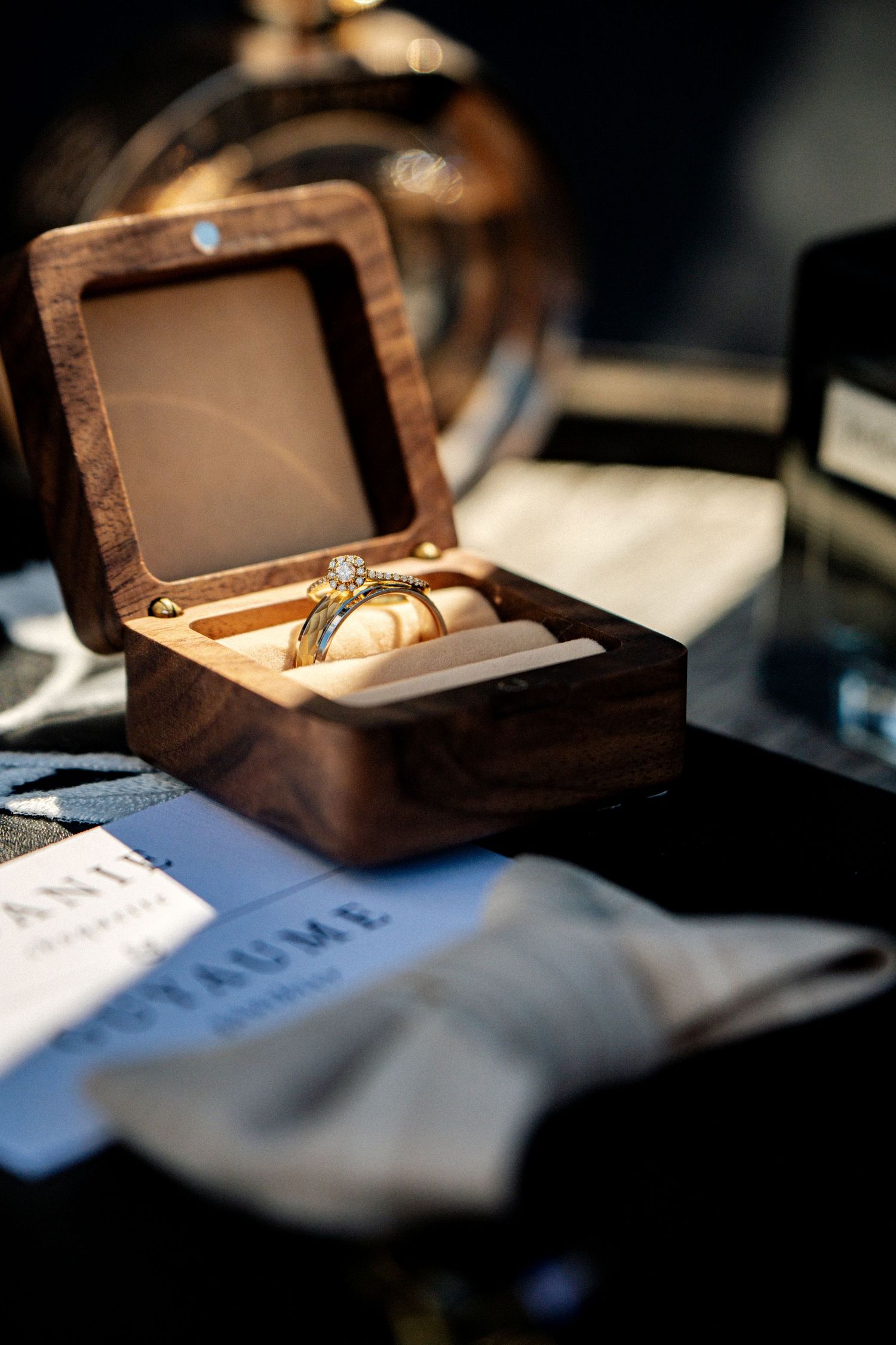 Elegant diamond engagement ring displayed in an open wooden ring box on a dark surface.