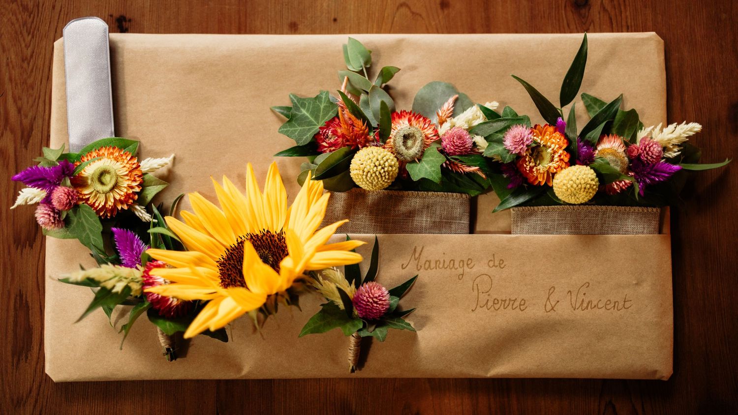 Brown kraft paper gift wrap adorned with sunflowers, wildflowers, and greenery, with handwritten calligraphy text.