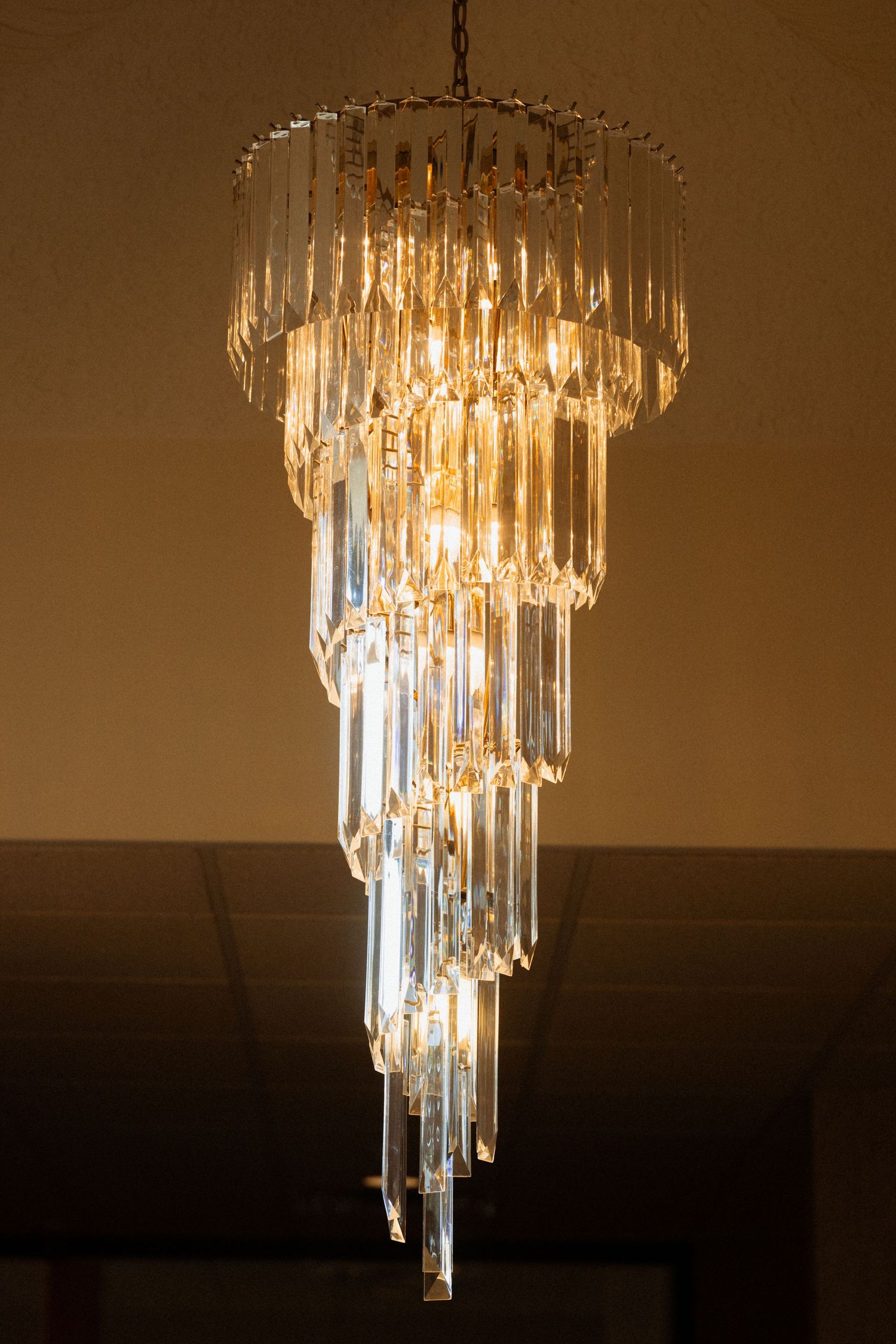 Elegant spiral crystal chandelier with warm glowing lights hanging from ceiling.