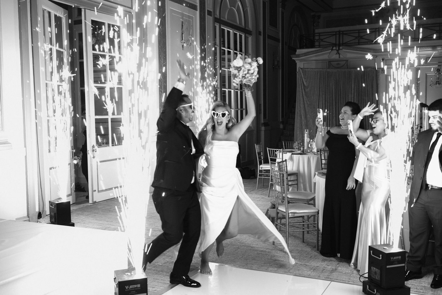 Bride and groom celebrating grand reception entrance with cold sparkler fountains in black and white.