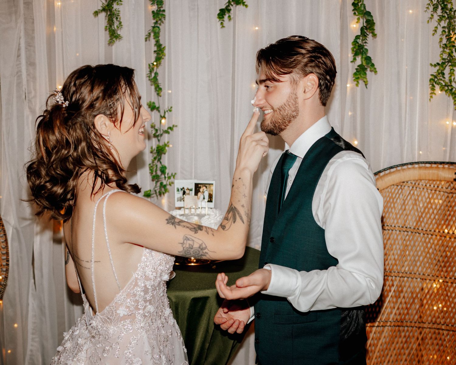 Bride tenderly touches groom's face during emotional wedding ceremony with greenery backdrop.