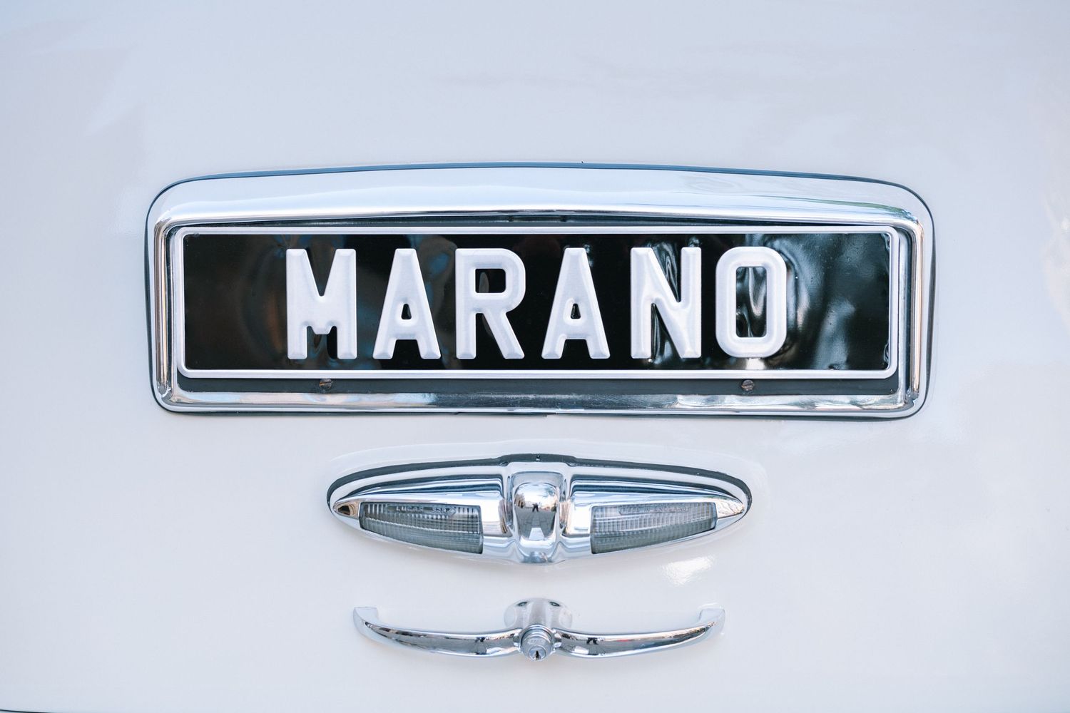 Vintage white classic wedding car with custom MARANO license plate chrome detail close-up shot.