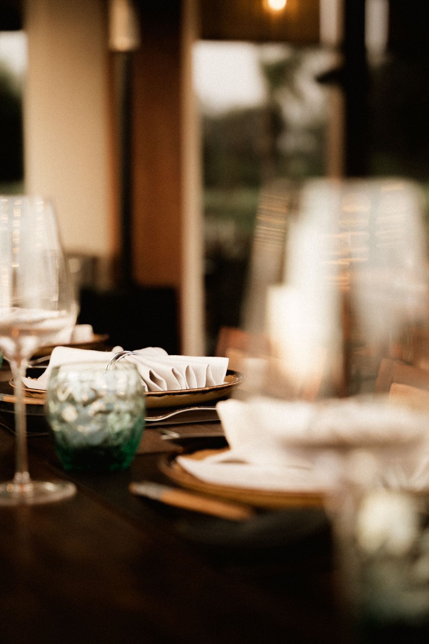 Elegant fine dining table setting with wine glasses, napkins, and warm ambient lighting.