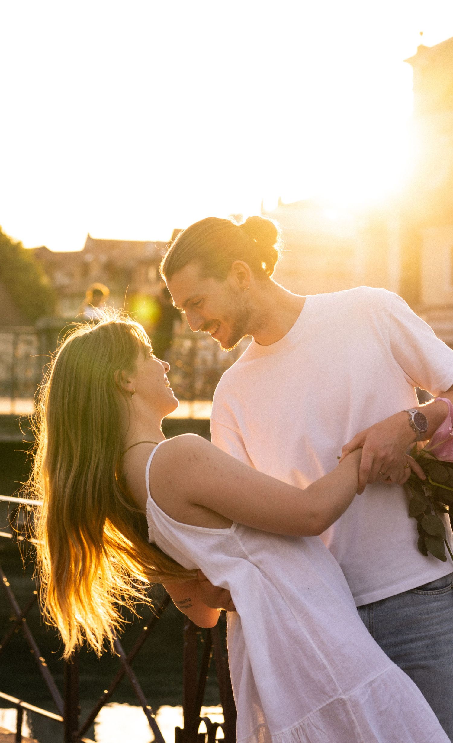 Happy couple embracing and smiling at each other during a warm golden hour sunset.