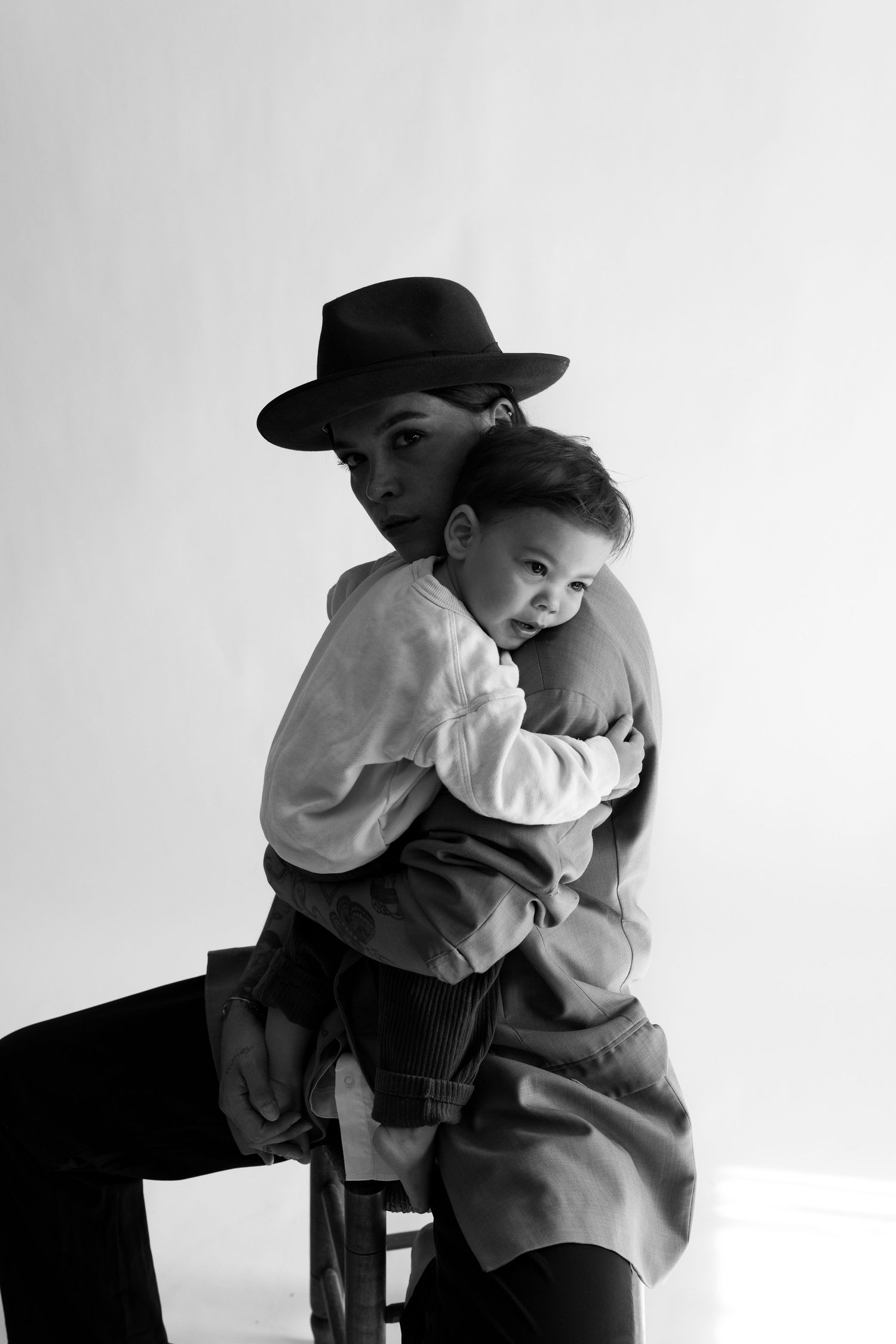 Black and white studio portrait of a woman wearing a hat tenderly holding a baby.