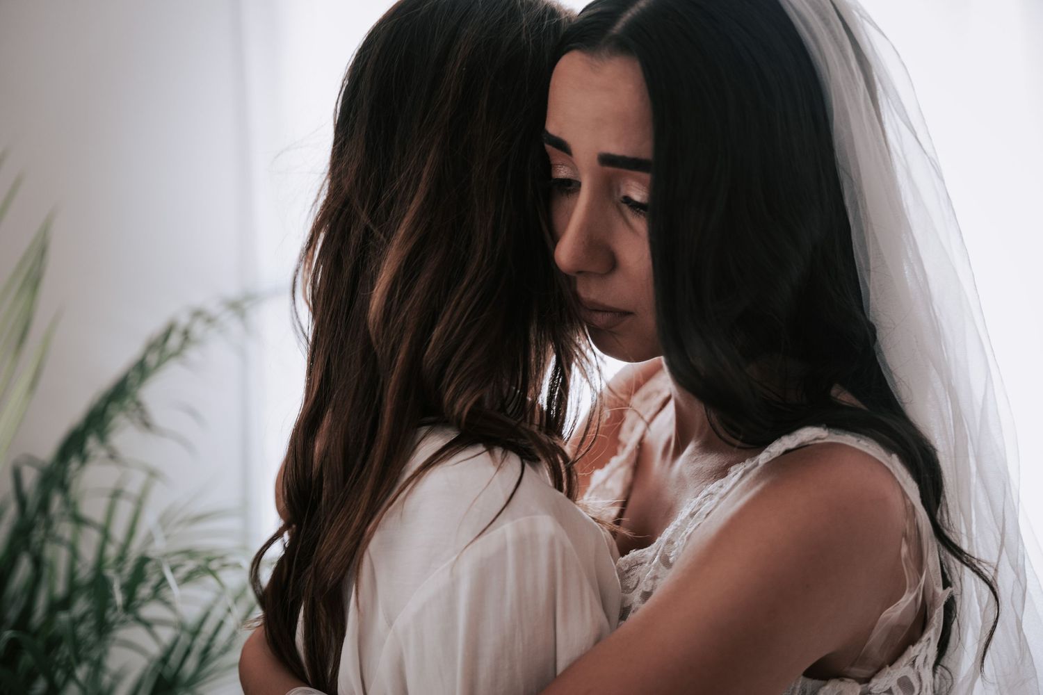 Two women sharing an emotional embrace in bridal getting-ready moment before wedding ceremony.
