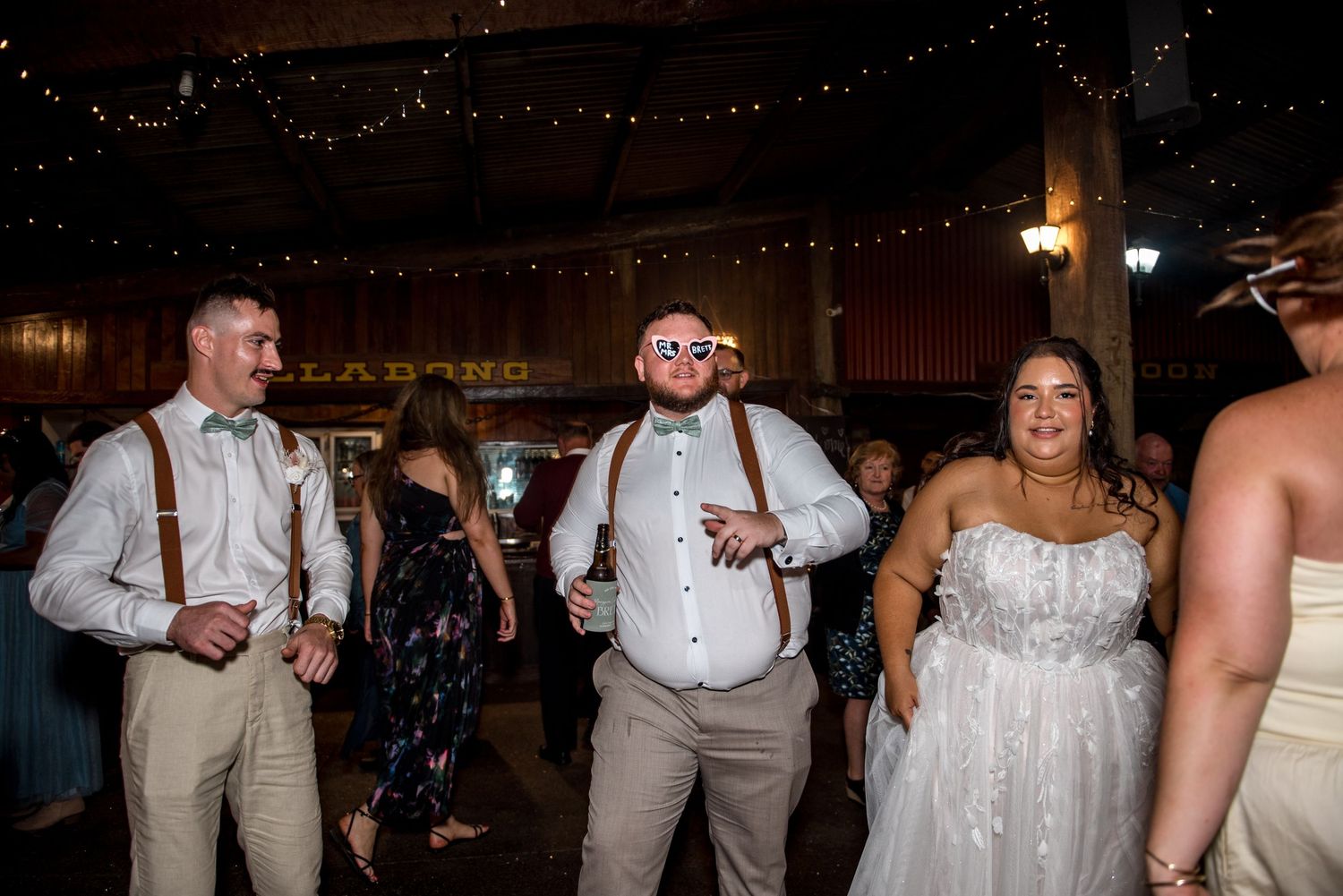 Wedding party guests dancing and celebrating on the dance floor at an evening reception.