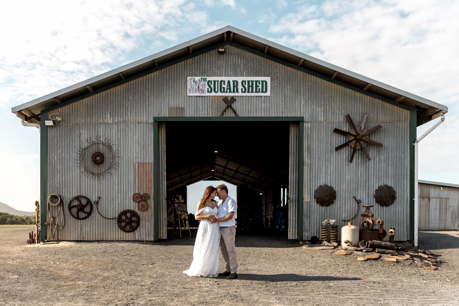 Bride and groom embracing in front of a rustic Sugar Shed barn venue on their wedding day.