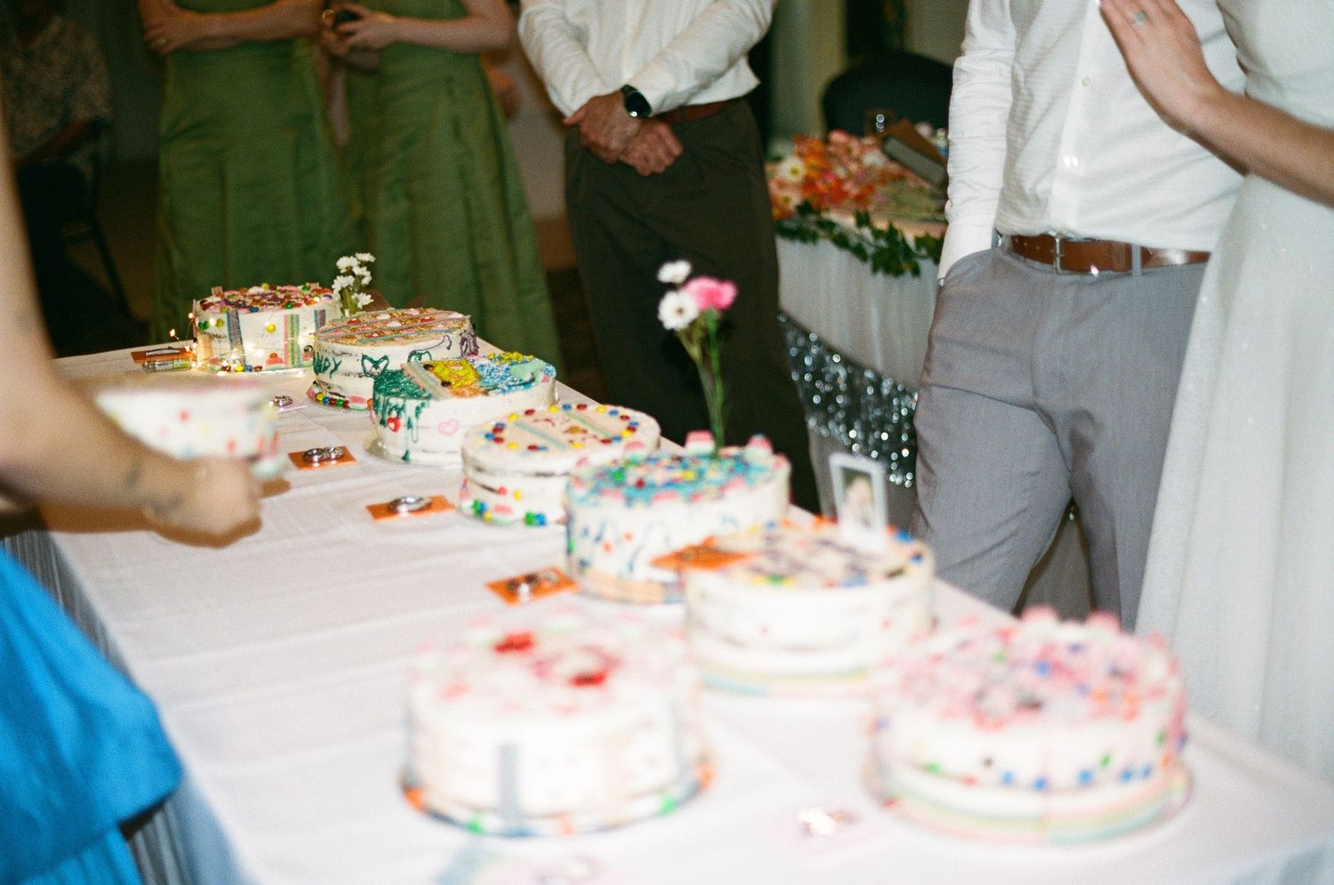 Multiple decorated wedding cakes displayed on white tablecloth at reception dessert table.