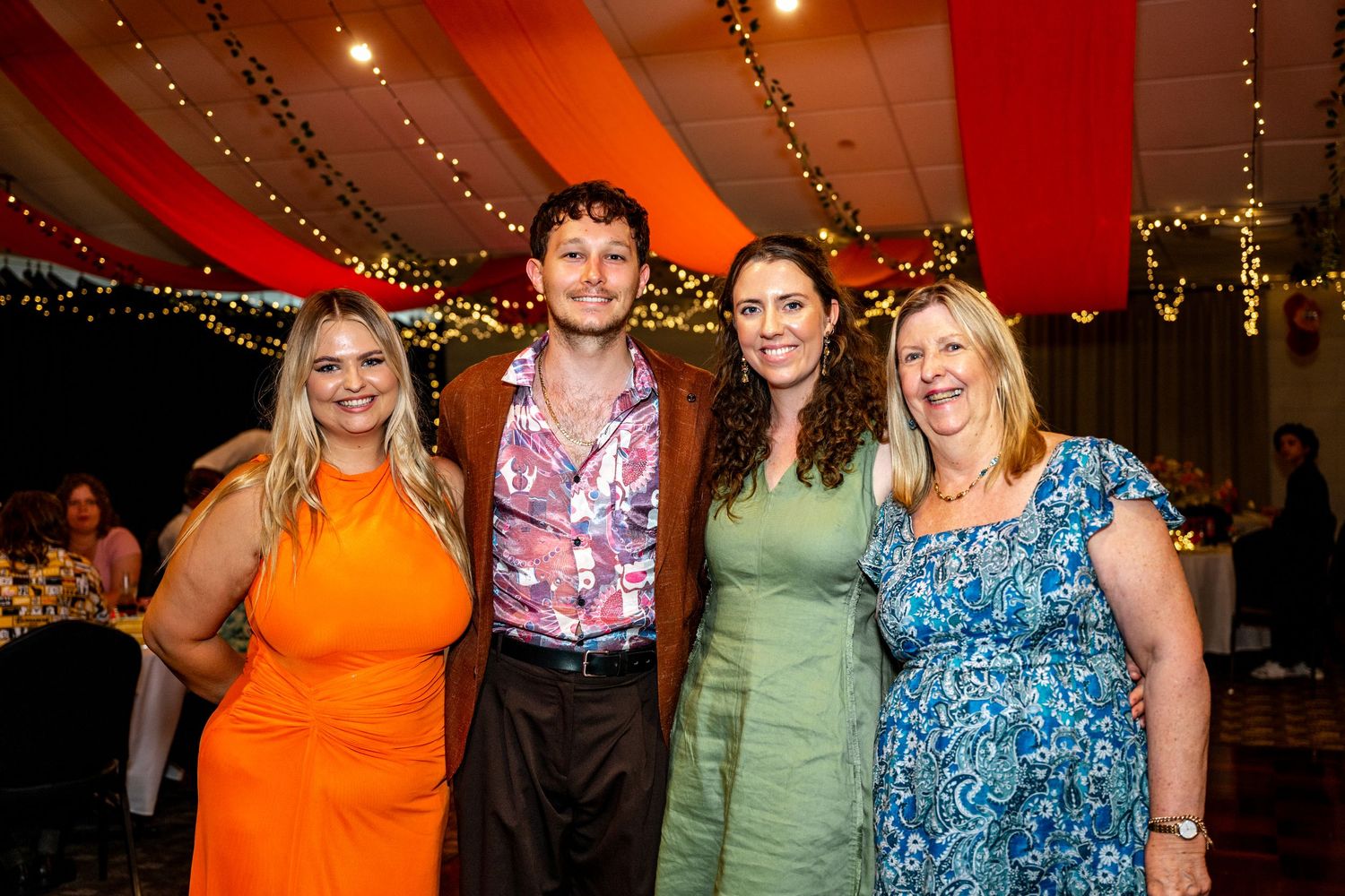 Group of four guests smile together at a decorated wedding reception.