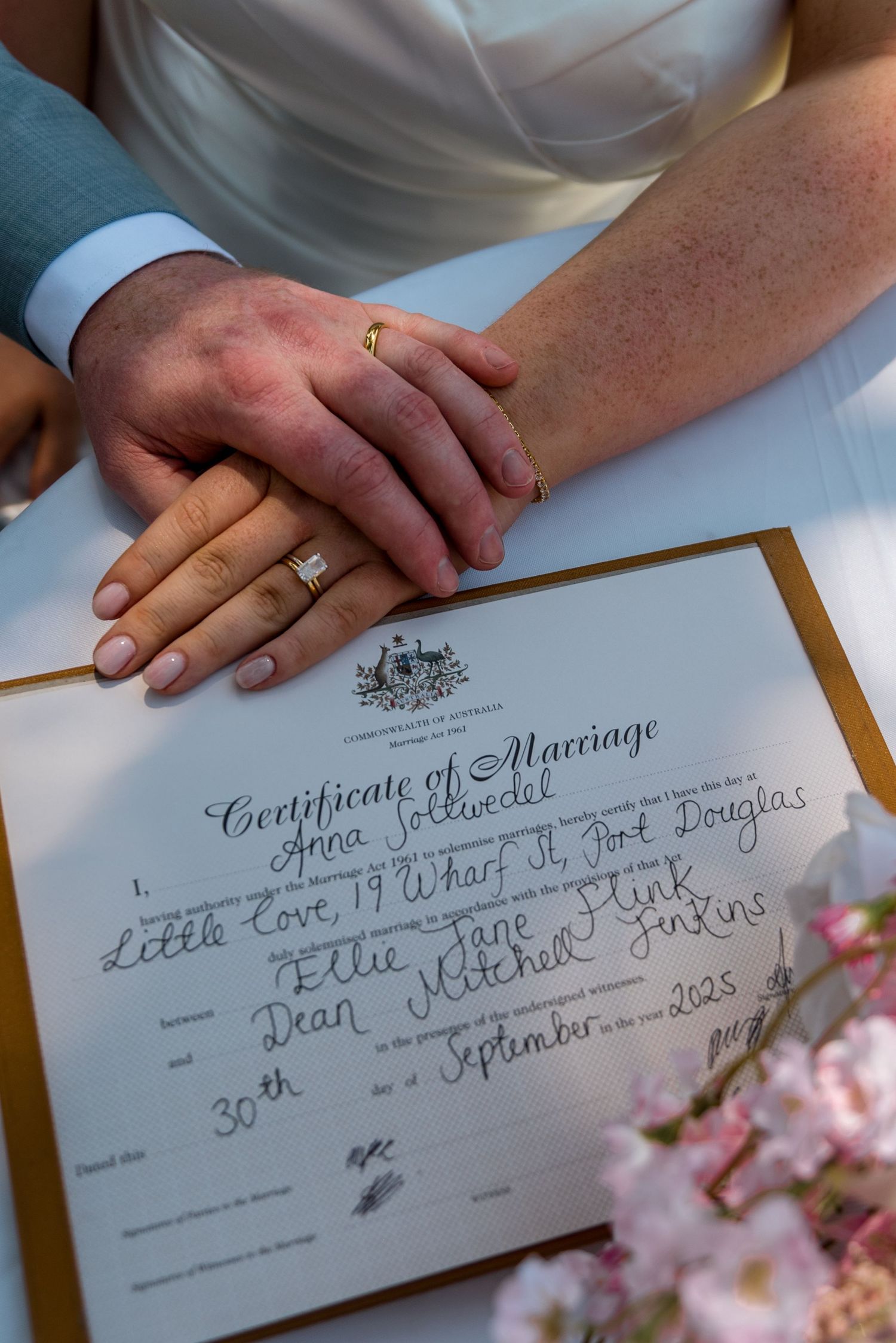 Newlyweds hands resting on Australian Certificate of Marriage signed on 30th September 2023 in Port Douglas.