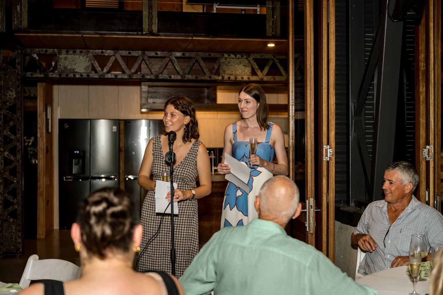 Two women giving a toast speech at a wedding reception dinner.