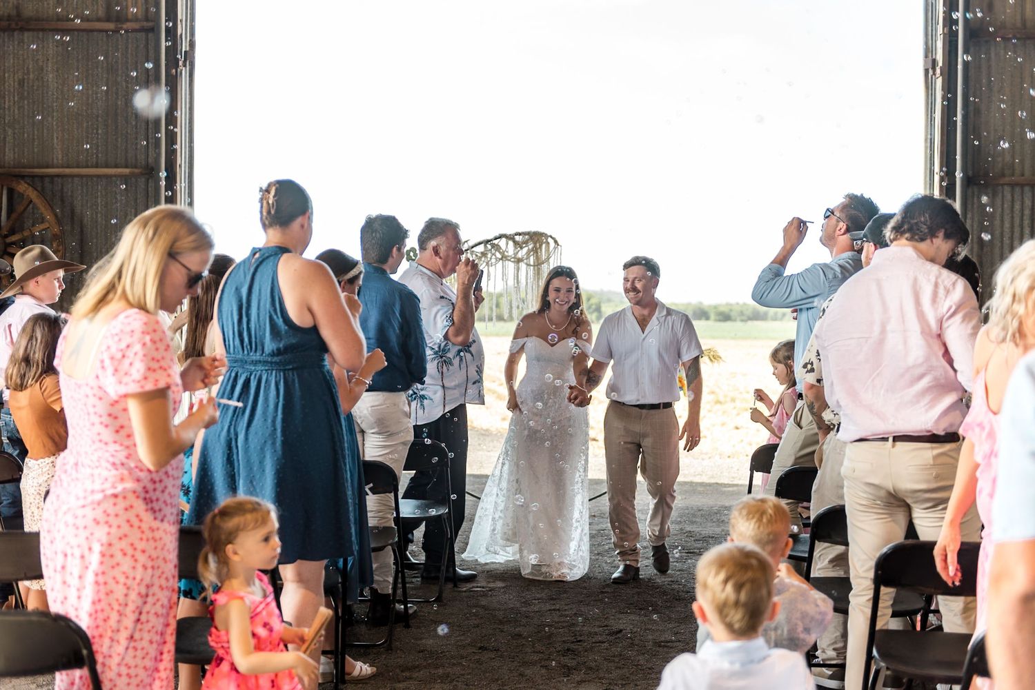Bride and groom walk down the aisle at a rustic barn wedding celebration.