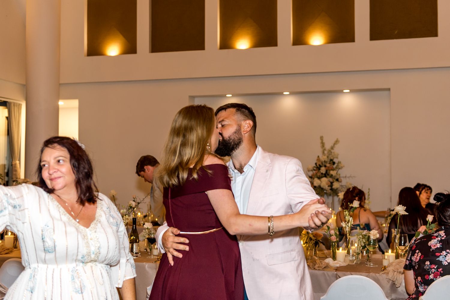 Couple sharing romantic dance at wedding reception in white venue with floral decorations.