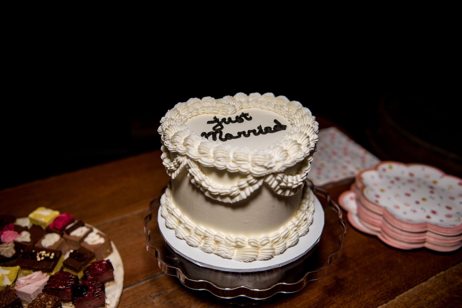 Two-tier white wedding cake decorated with just married inscription and elegant piped details.