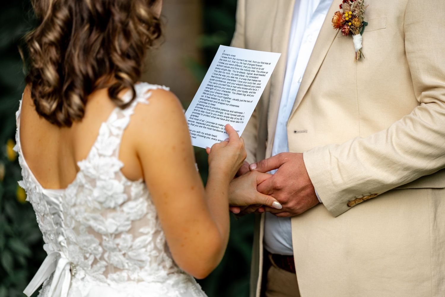 Bride and groom exchange handwritten vows during intimate outdoor wedding ceremony in garden setting.