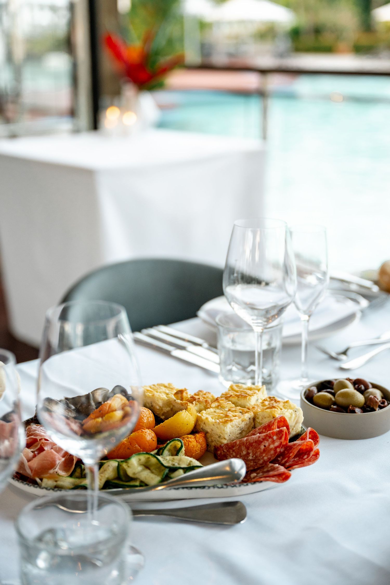 Elegant wedding reception table set with antipasto platter, wine glasses, and pool view backdrop at Sheraton Grand Mirage Port Douglas.