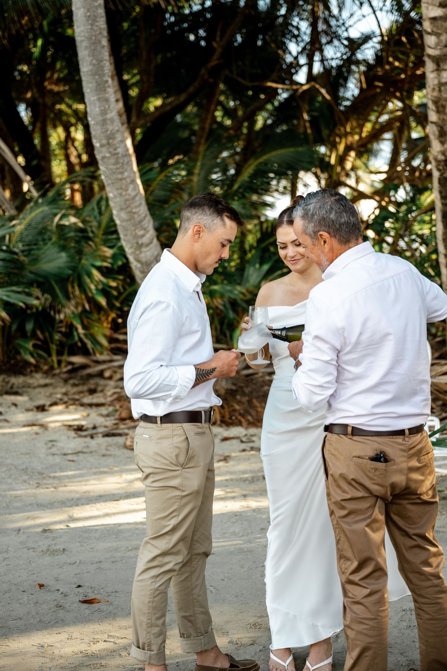 Officiant performing beach wedding ring exchange ceremony with bride and groom at Four Mile Beach, Port Douglas.