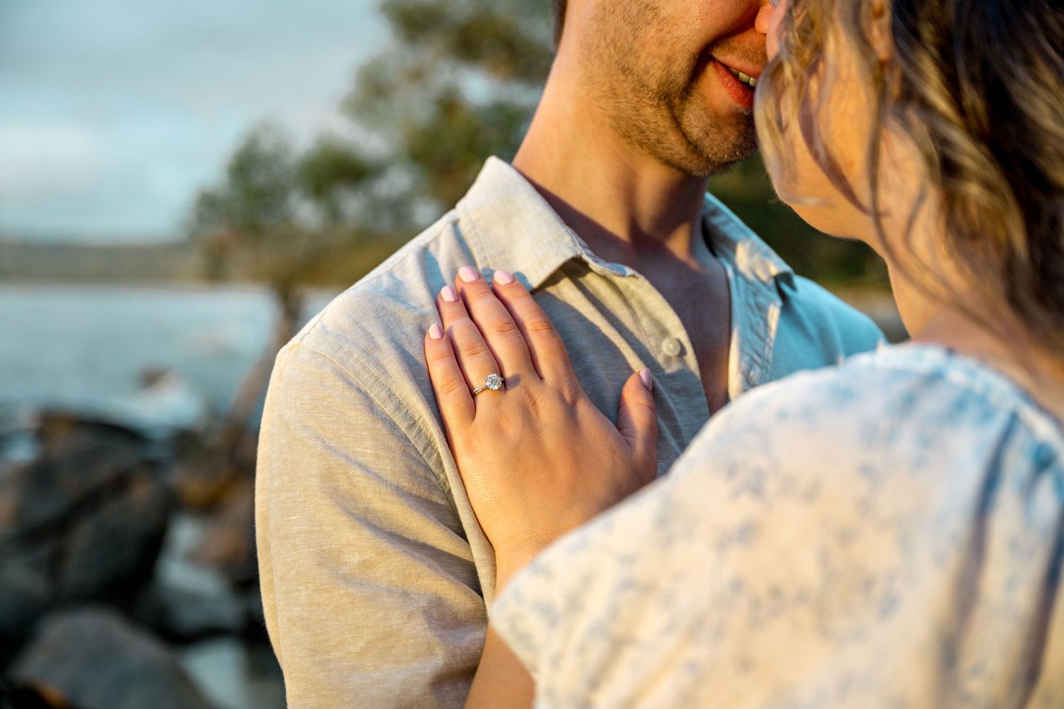 Close-up of engaged couple nearly kissing with woman's hand showing diamond ring on man's chest at Four Mile Beach, Port Douglas.