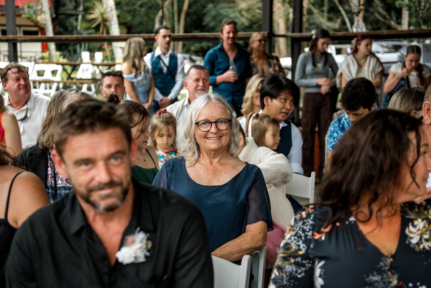 Wedding guests mingling and seated at an outdoor rustic wedding venue ceremony.