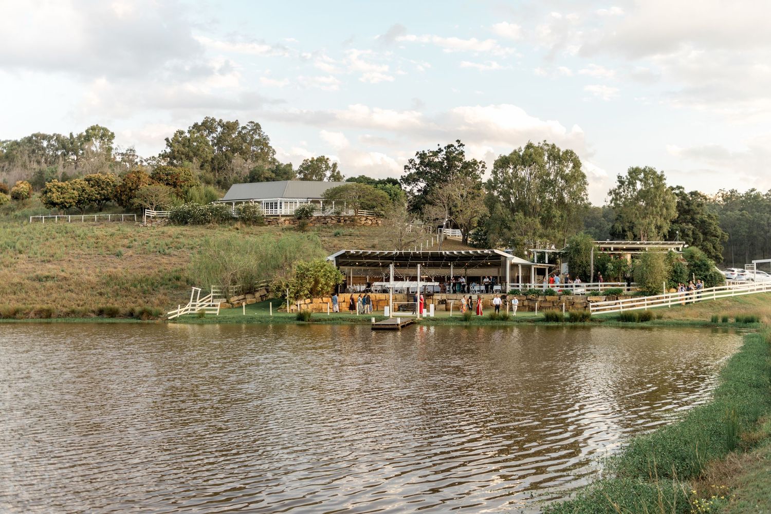 Scenic wedding venue with a lakeside pavilion surrounded by lush trees and calm water.