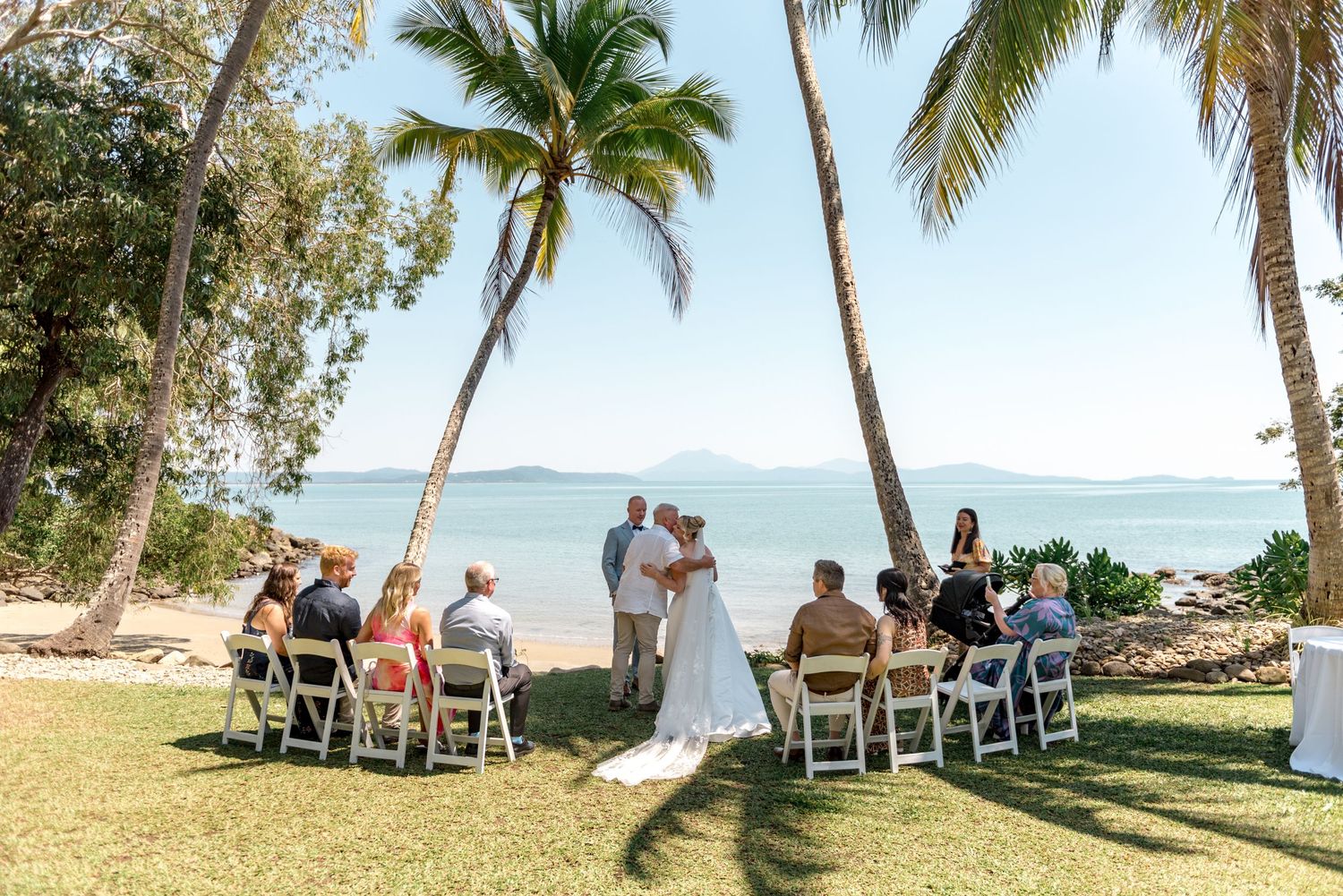 Couple exchanges vows at intimate outdoor beach wedding ceremony surrounded by tropical palm trees.