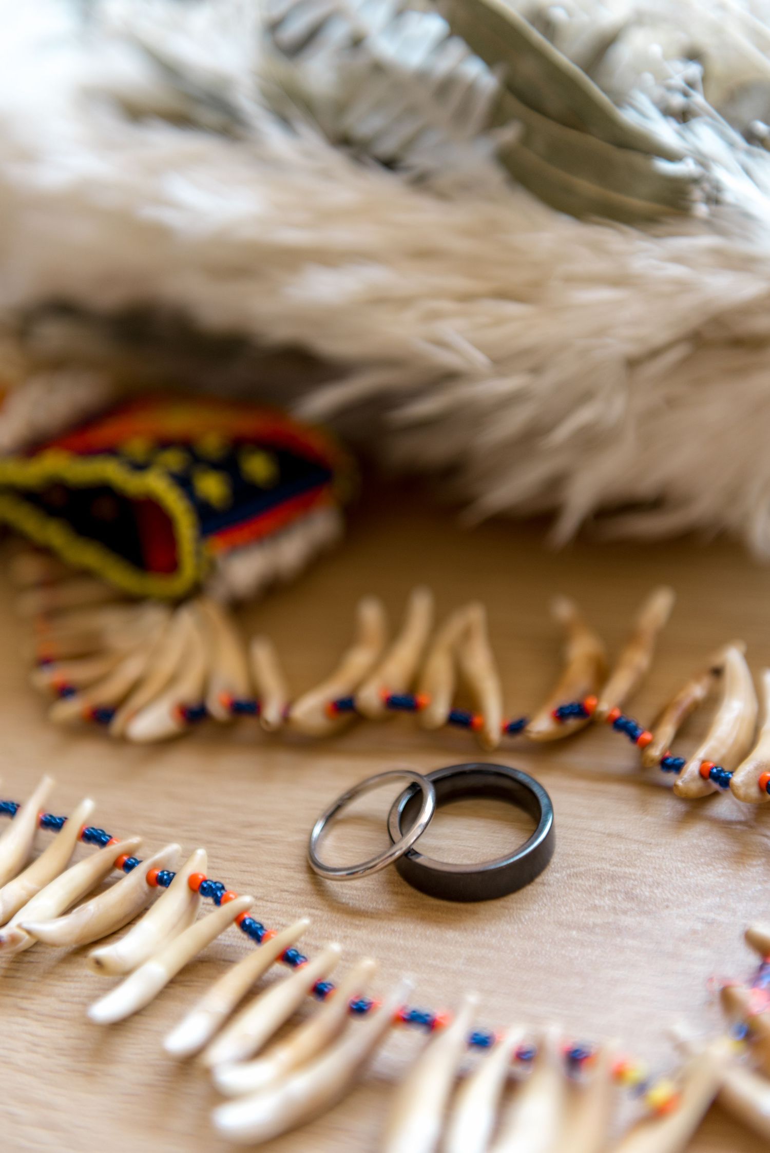 Two wedding bands displayed on a wooden surface surrounded by beaded Native American ceremonial items.