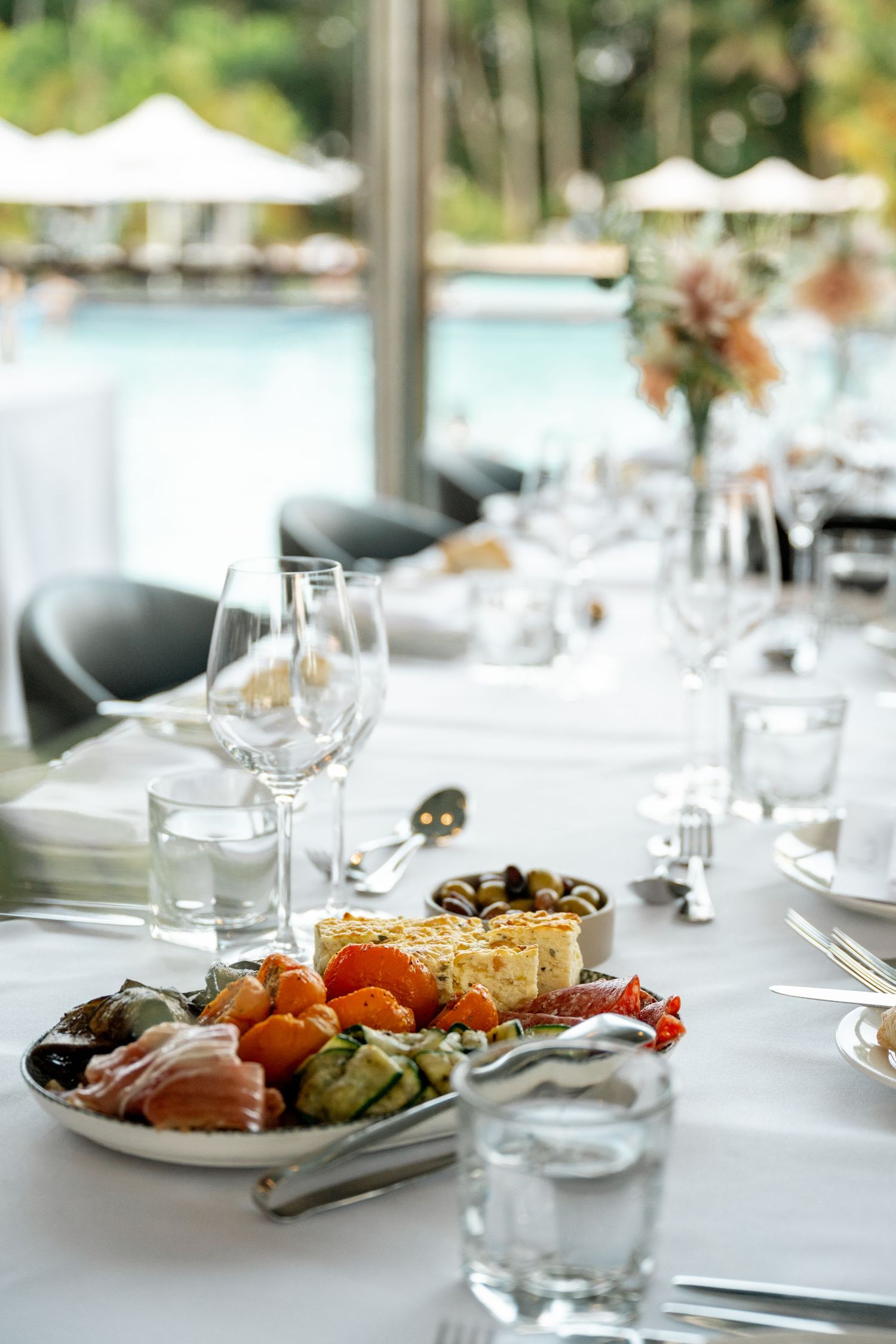 Elegant wedding reception table with antipasto platter, wine glasses, and tropical pool backdrop at Sheraton Grand Mirage Port Douglas.