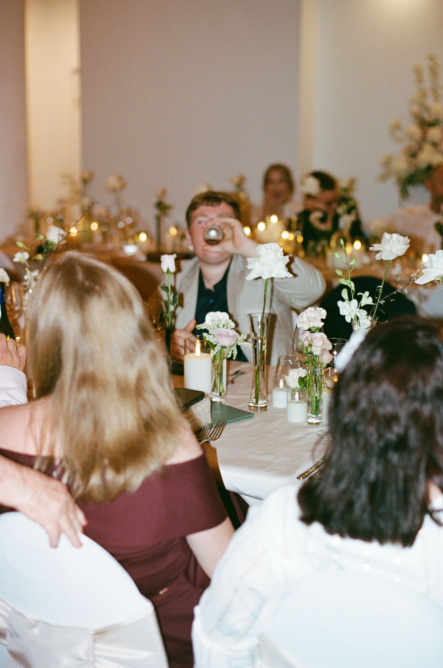 Wedding guest raising a glass for a toast at a candlelit reception.