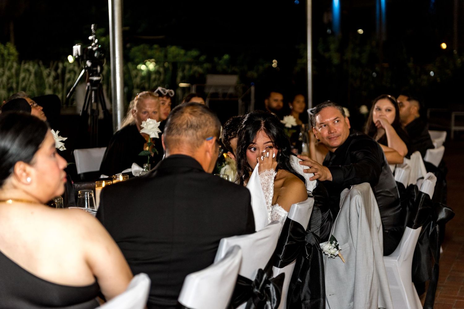 Wedding guests seated at outdoor reception tables sharing joyful moments.