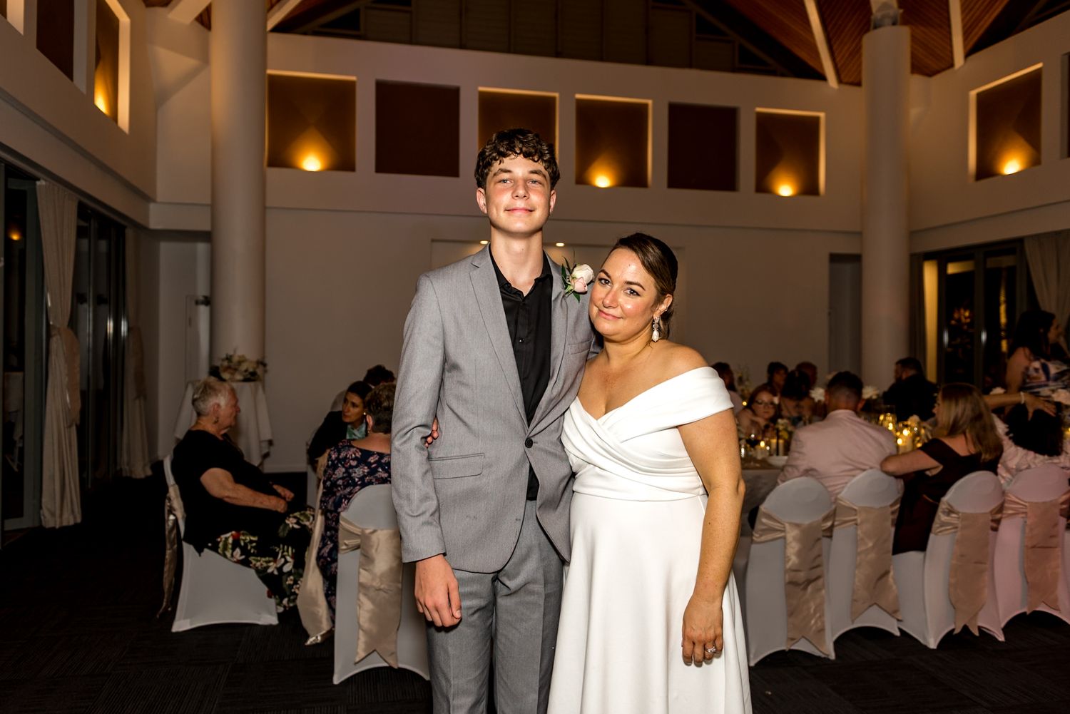 Young couple posing together at wedding reception in elegant venue with warm lighting.
