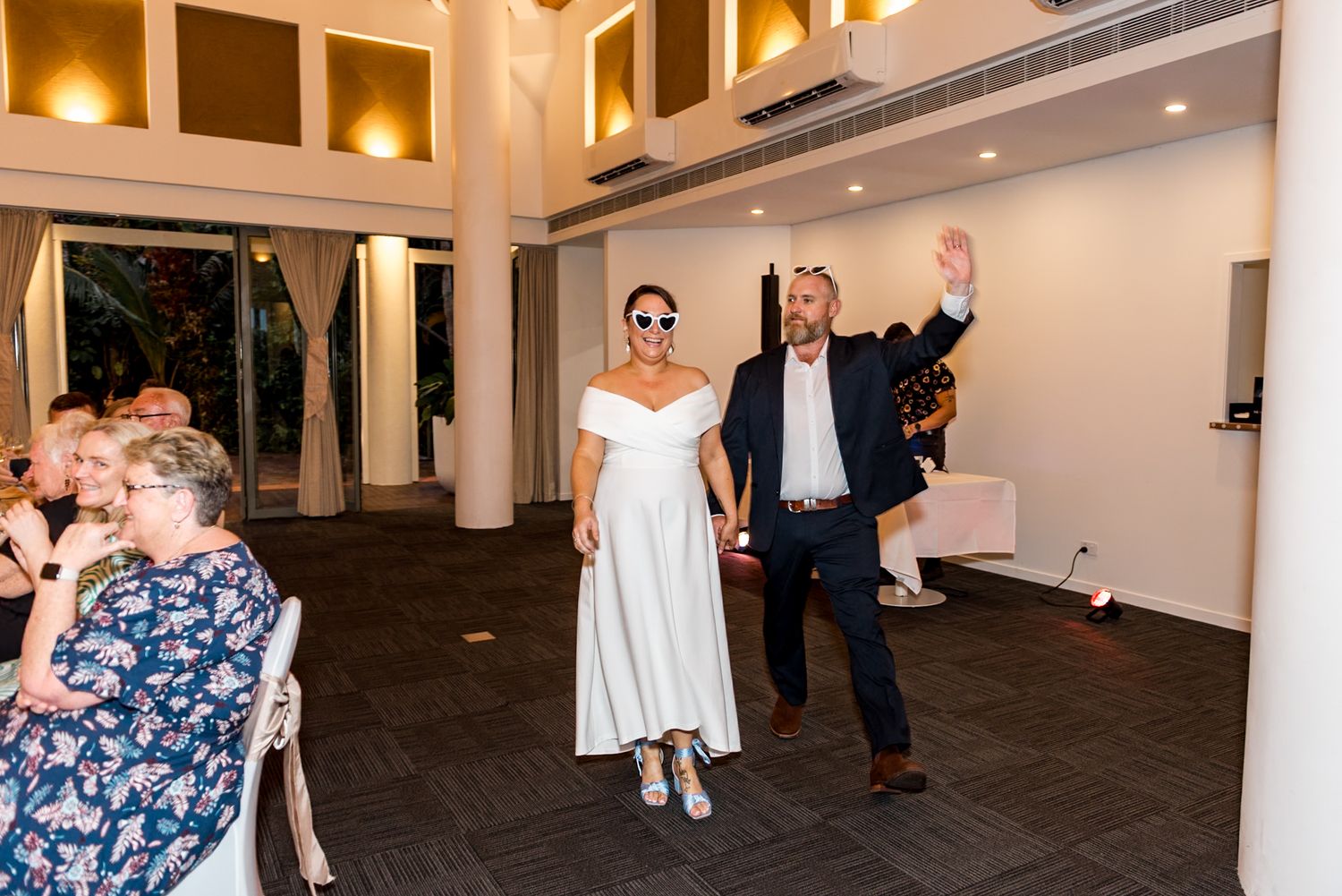 Bride and groom making a grand entrance into wedding reception as guests applaud and celebrate.