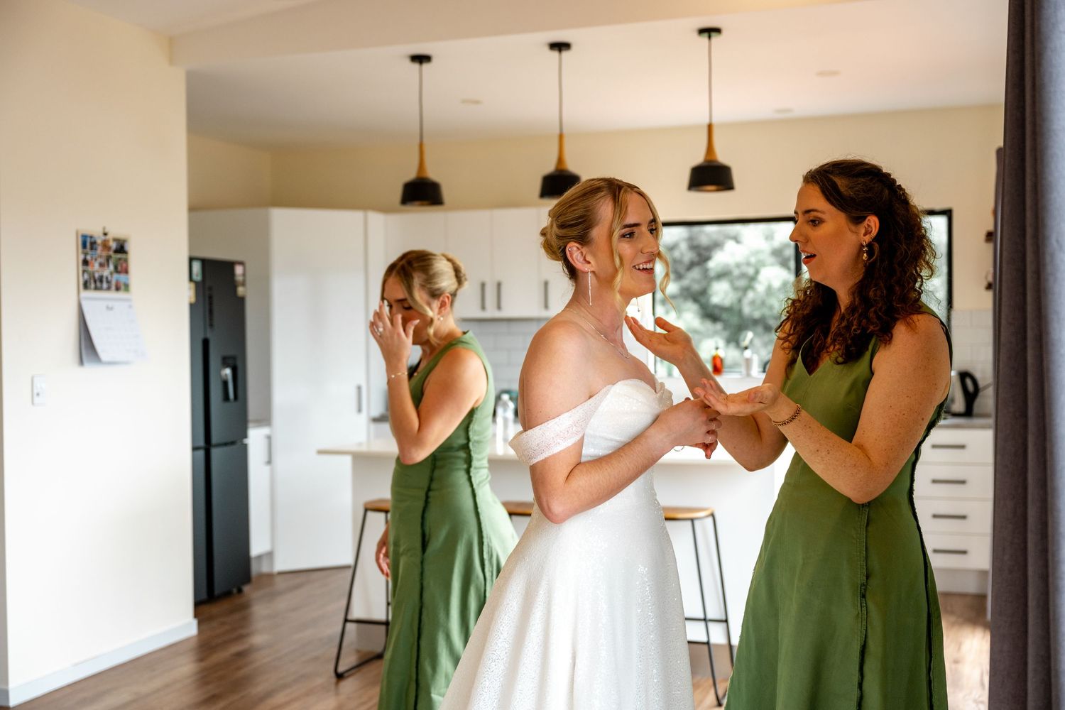 Bridesmaids in green dresses share emotional moment with bride during wedding preparations.