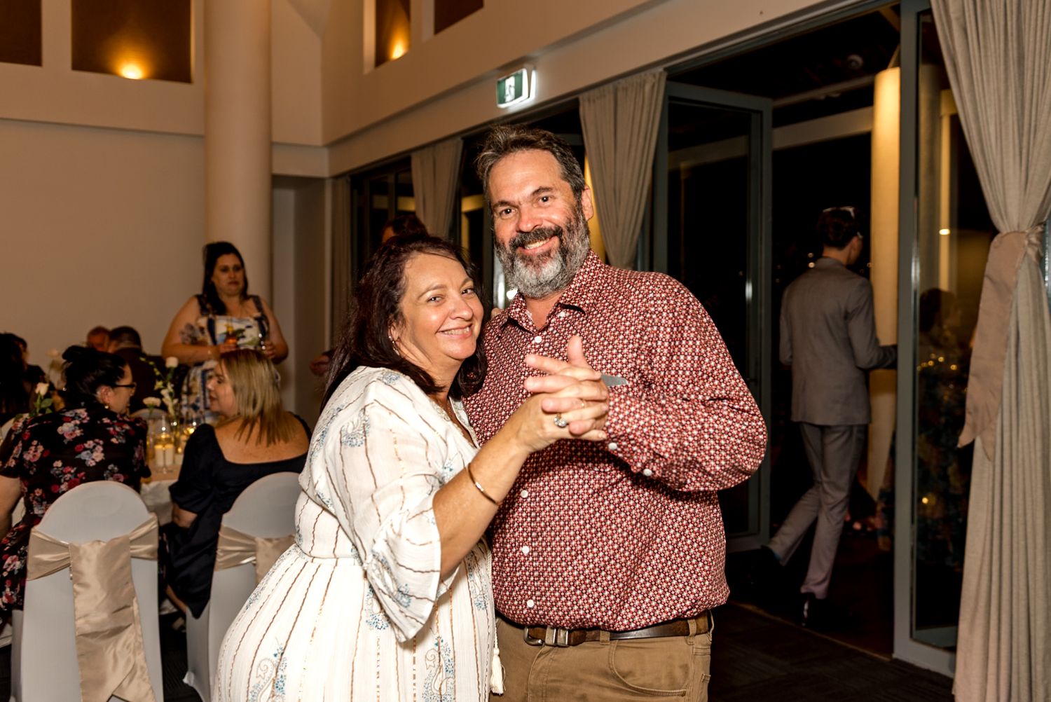 Smiling couple dancing together at wedding reception in elegant indoor venue.