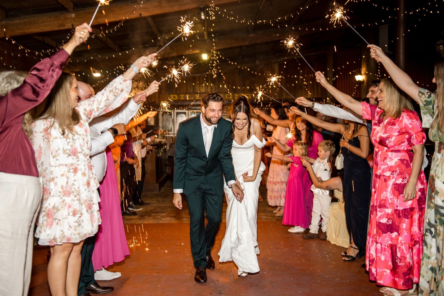 Newlyweds walking through a sparkler exit tunnel at their rustic wedding reception.