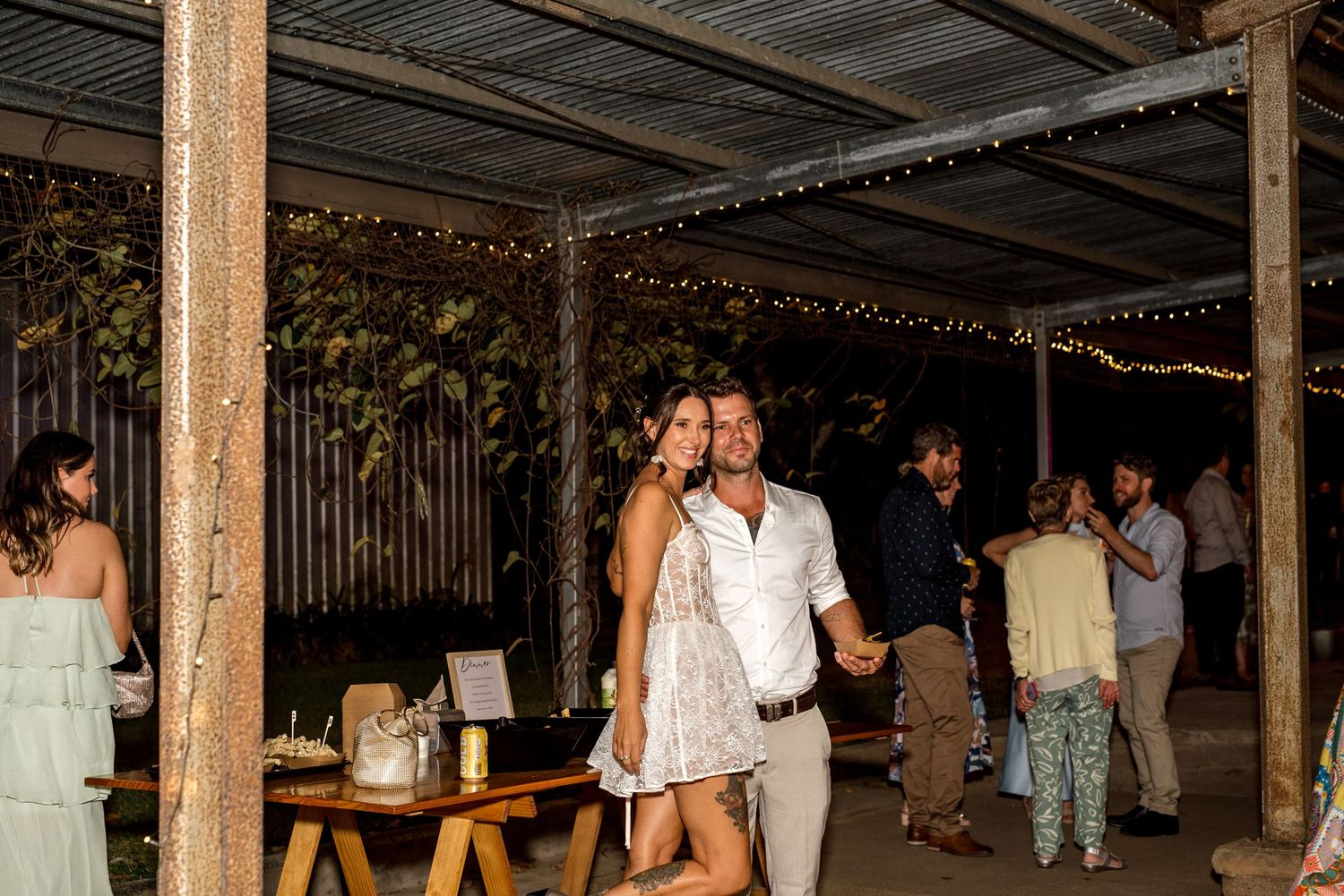 Couple dancing together at an outdoor rustic barn wedding reception with fairy lights.