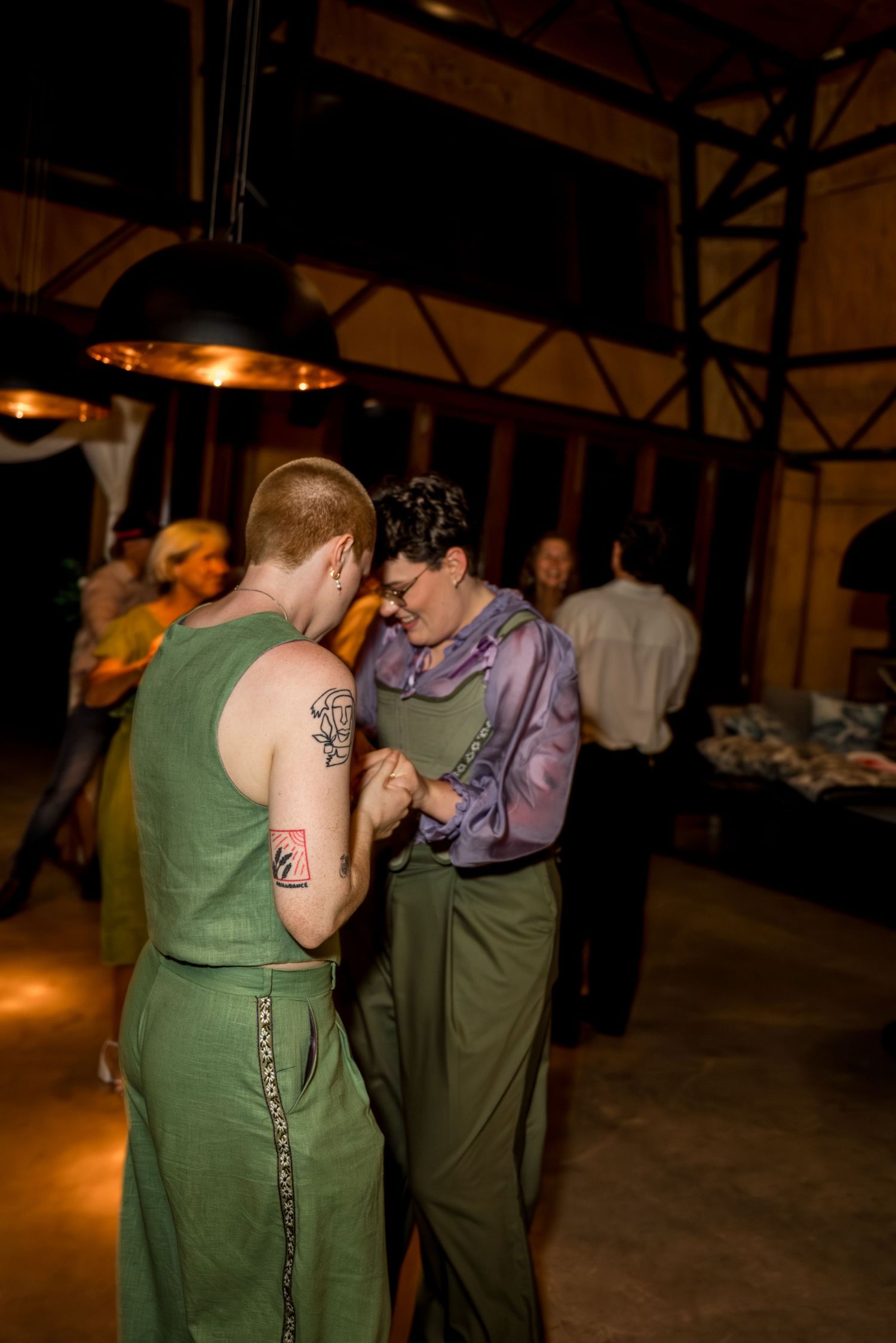 Couple in green and purple wedding outfits share an intimate dance at reception.