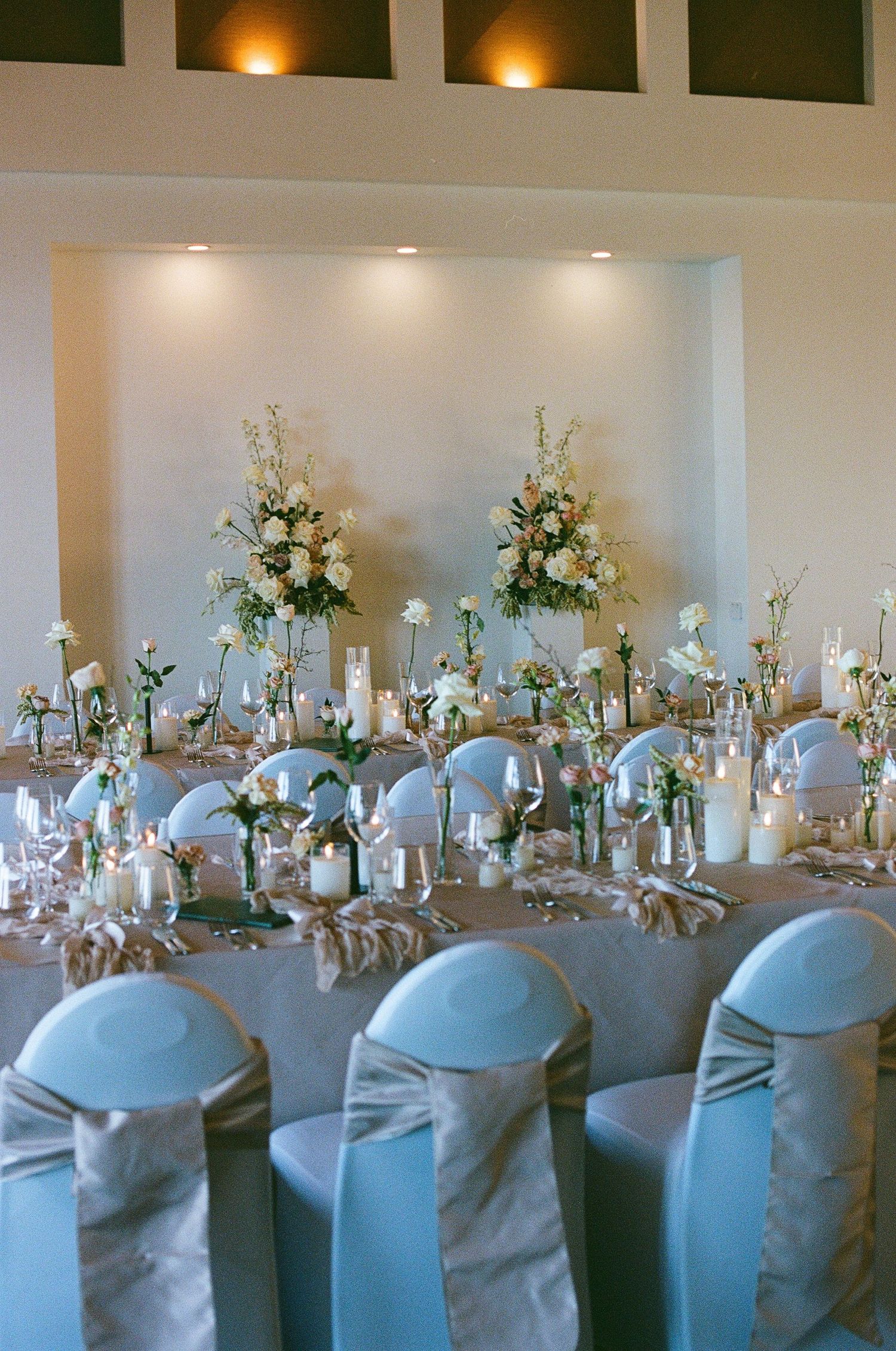 Elegant wedding reception table with white floral centerpieces and blue satin chair covers.